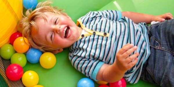 young boy playing in ball pit and laughing